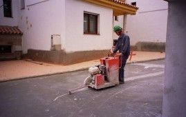 Un hombre está usando una máquina para hacer un agujero en la carretera.