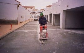 Un hombre está usando una máquina para cortar hormigón en un estacionamiento.