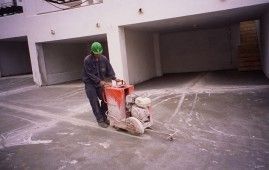 Un hombre está usando una máquina para cortar hormigón en un estacionamiento.