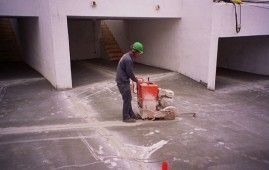 Un hombre está usando una máquina para cortar hormigón en un estacionamiento.