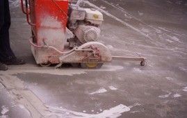 Una persona está usando una sierra de hormigón para cortar un agujero en el suelo.