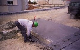Un hombre que lleva un casco verde está arrodillado al costado de una carretera.