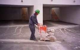 Un hombre está usando una sierra para cortar hormigón en un estacionamiento.