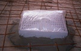 Una tapa de alcantarilla está envuelta en plástico y colocada encima de un piso de concreto.