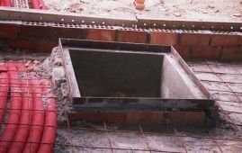 Una tapa de alcantarilla está colocada encima de una pared de ladrillos.