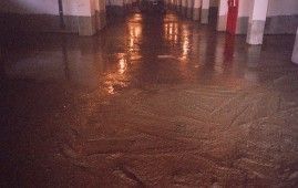 Una habitación oscura con suelo de cemento y una puerta roja.