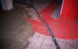 Se está utilizando una manguera para verter hormigón sobre un suelo de baldosas.