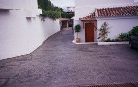 Un camino de entrada que conduce a una casa con un coche aparcado delante.