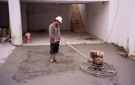 Un hombre está usando una máquina para nivelar un piso de concreto.