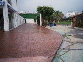 Una pasarela de ladrillos que conduce a un edificio con una manguera al costado.