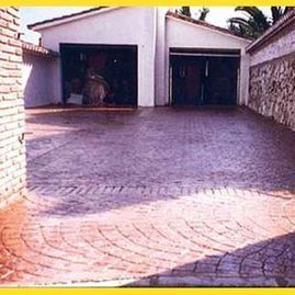 Un camino de entrada con una pared de ladrillo y un garaje al fondo.