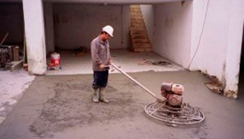 Un hombre está utilizando una máquina para nivelar el hormigón en un garaje.