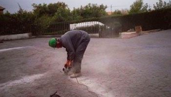 Un hombre está usando una motosierra para cortar un agujero en el suelo.