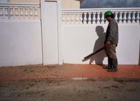 Un hombre está parado frente a una pared blanca sosteniendo una escoba.