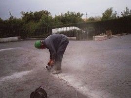 Un hombre está utilizando una amoladora sobre una superficie de hormigón.