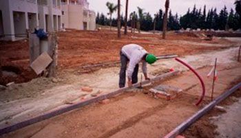 Un trabajador de la construcción está trabajando en una acera en un sitio de construcción.