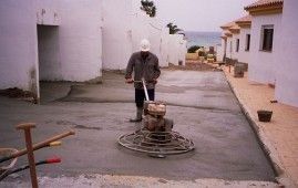 Un hombre está usando una máquina para nivelar un camino de entrada de concreto.