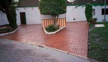 Un camino de ladrillo que conduce a una casa con un árbol en el medio.
