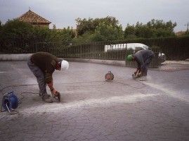 Dos hombres están trabajando en un camino de entrada de hormigón.