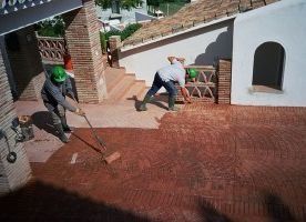 Dos hombres están pintando un patio con un rodillo.