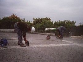 Dos hombres están trabajando en un camino de entrada de hormigón.