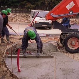 Un grupo de trabajadores de la construcción está trabajando en un piso de concreto.