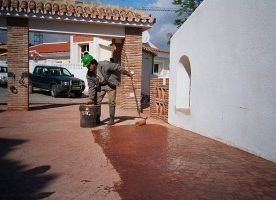 Un hombre está limpiando un camino de entrada con una escoba.