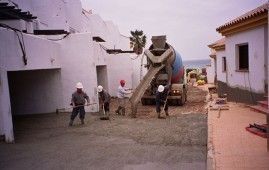 Un grupo de trabajadores de la construcción está parado frente a un camión de cemento.