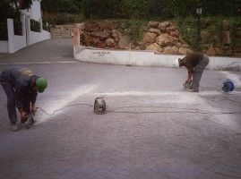 Dos hombres están trabajando en un camino de entrada de hormigón.