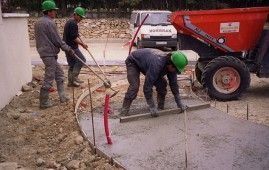 Un grupo de trabajadores de la construcción está trabajando en un camino de entrada de hormigón.