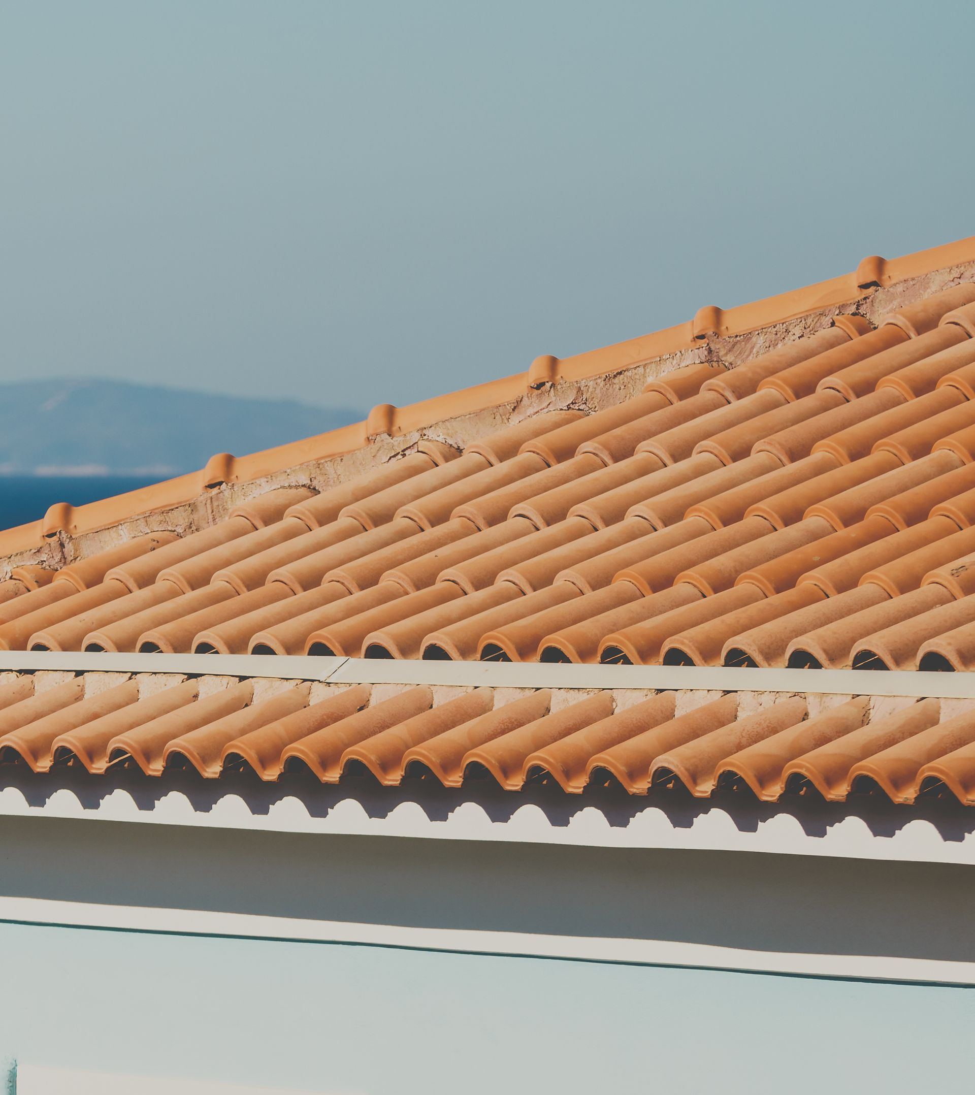 Toit de tuiles orange avec une planche de rive blanche.