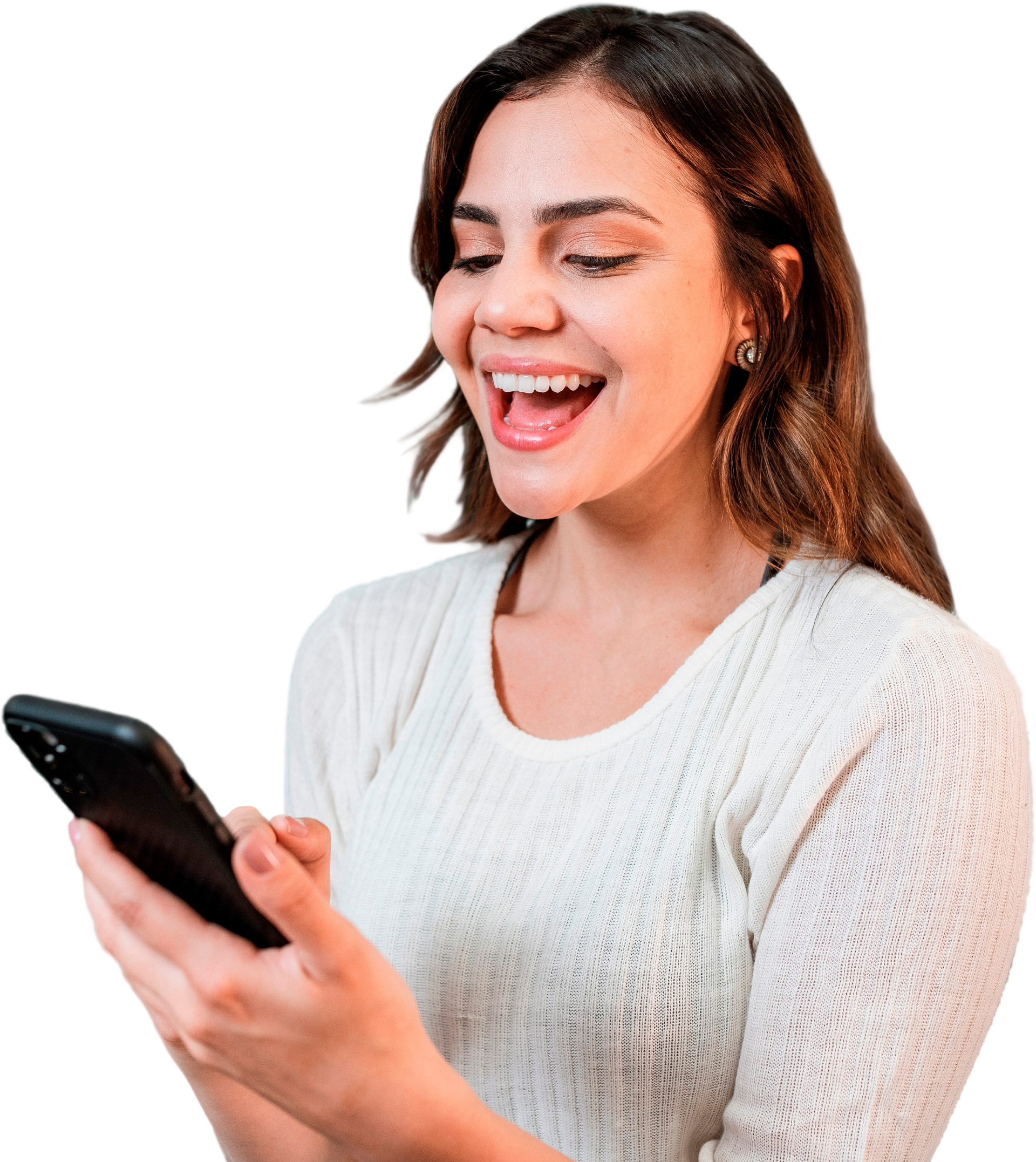 Une femme souriante regarde son smartphone, à l'extérieur. Elle porte un pull blanc.