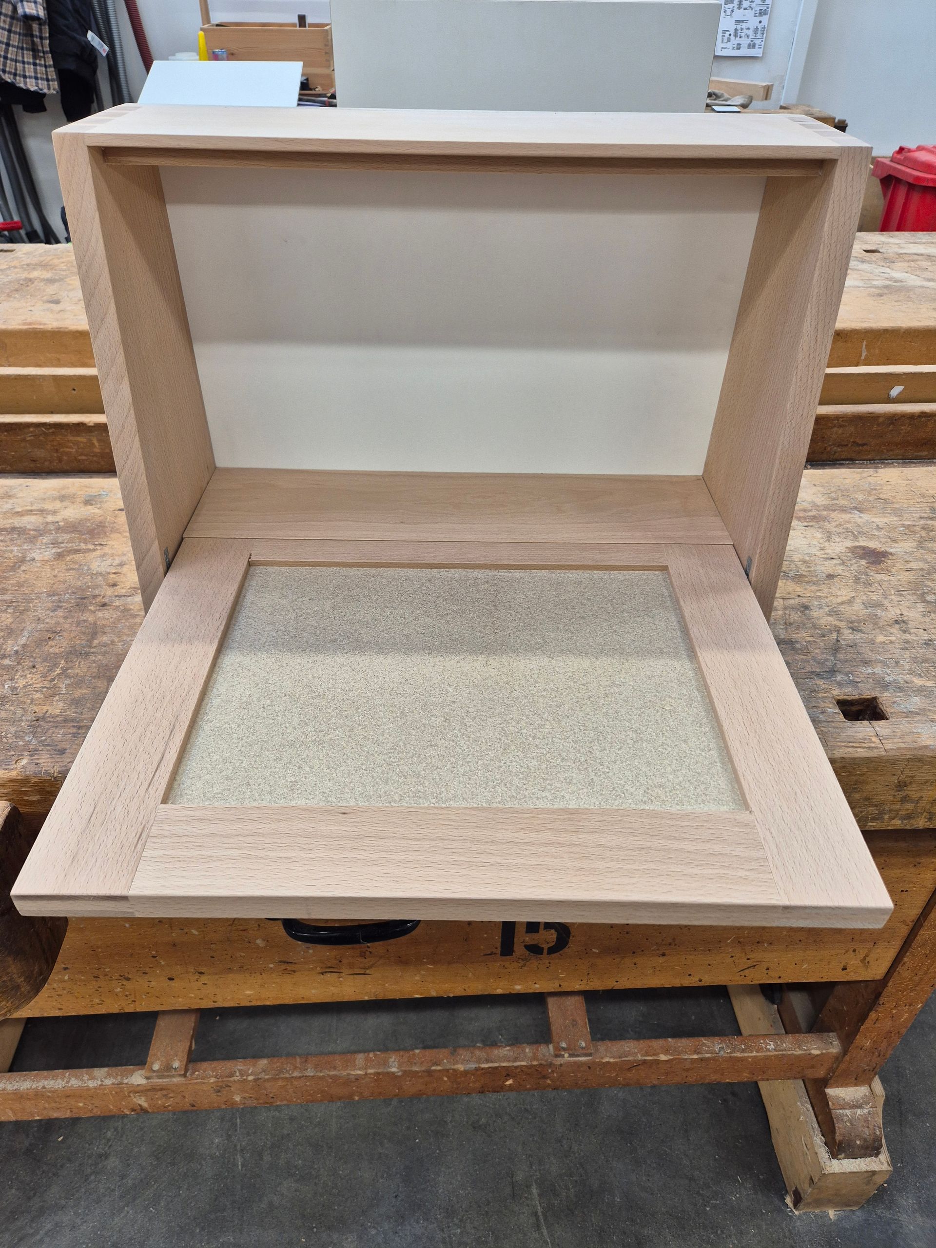 Holzrahmen mit eingelassener quadratischer Fläche, liegend auf einer Werkbank.