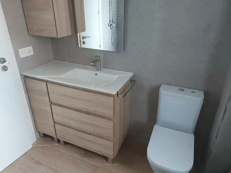 Un baño con lavabo, inodoro y espejo.