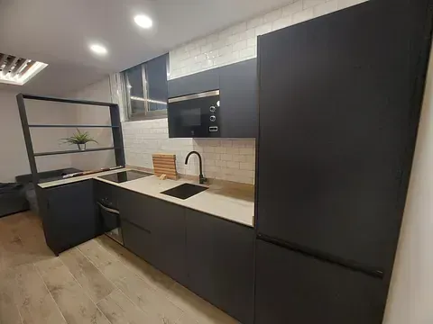 Una cocina con gabinetes negros, un fregadero, un refrigerador y un microondas.