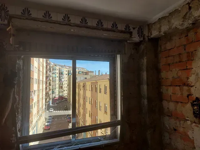 Una habitación con una pared de ladrillo y una ventana con vista a una ciudad.