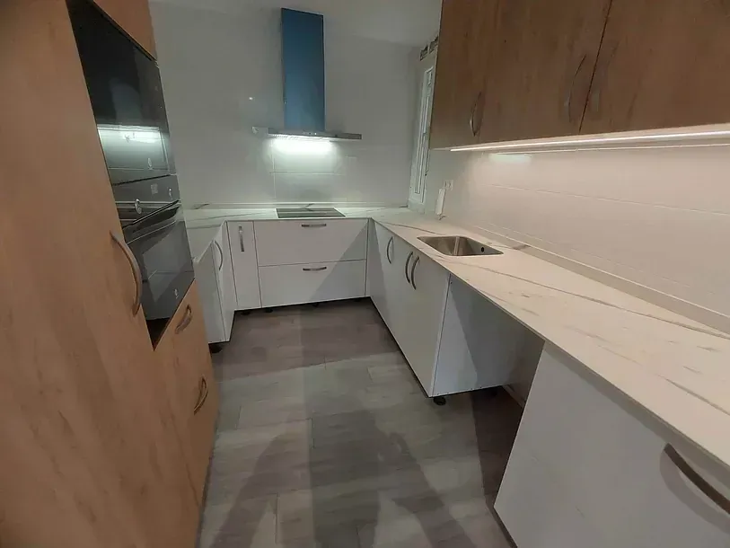 Una cocina con gabinetes de madera y encimeras blancas.