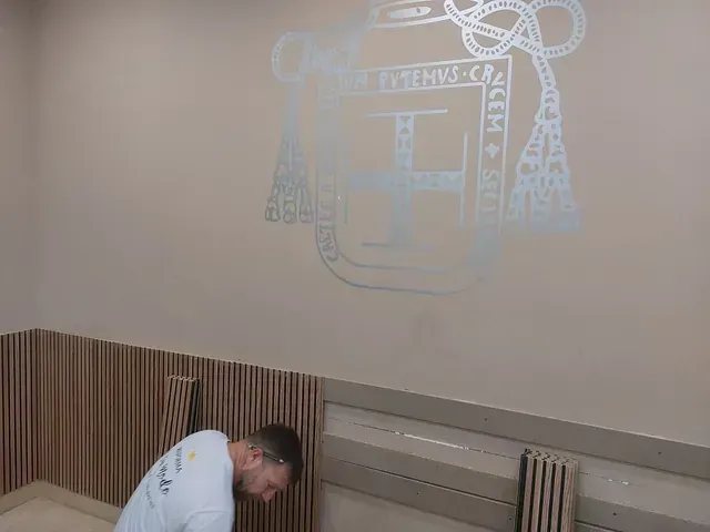 Un hombre está arrodillado frente a una pared con un dibujo en ella.