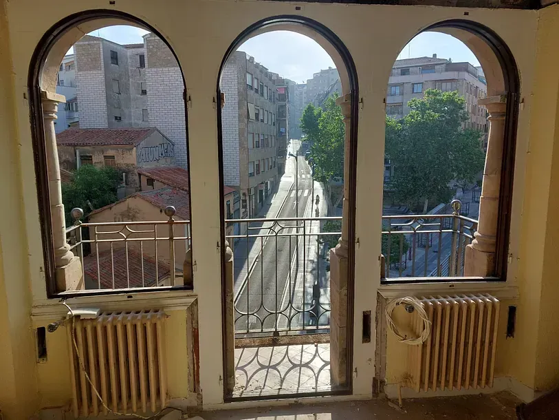 Una habitación con balcón y vista a la ciudad.