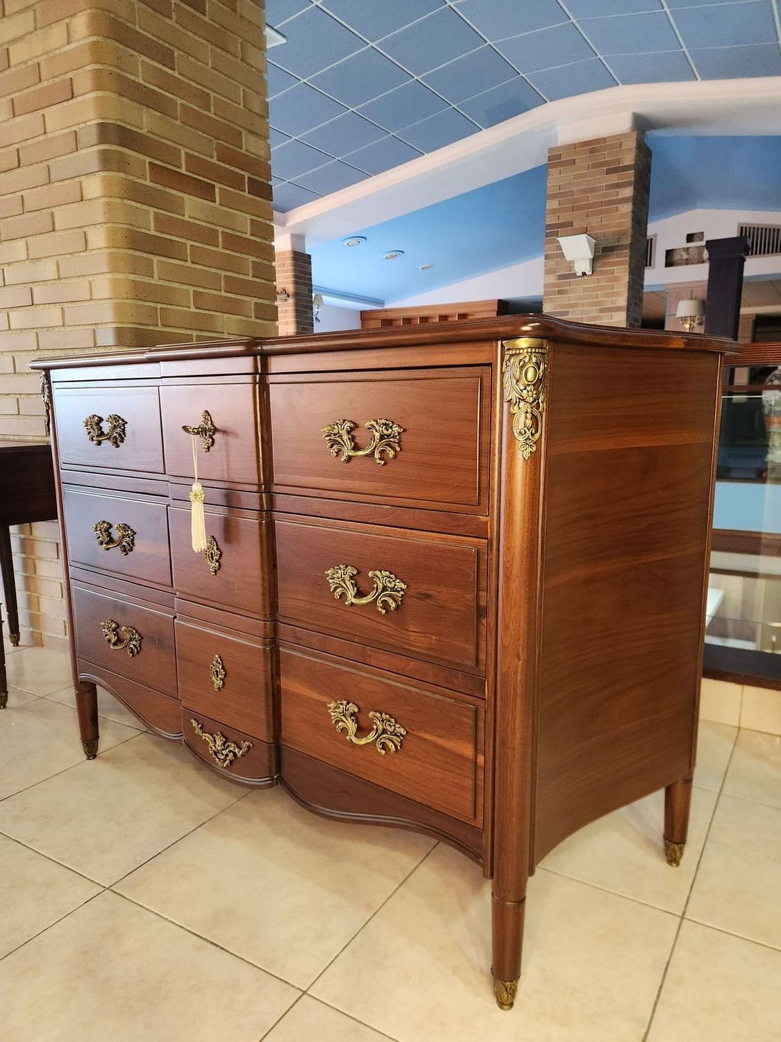 Cómoda de madera con herrajes ornamentados y cajones curvos.