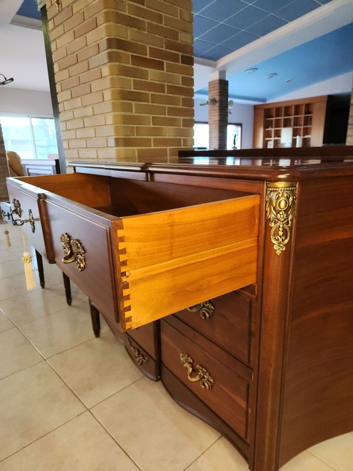 Cómoda de madera con un cajón abierto con juntas de cola de milano. La cómoda tiene herrajes de latón.