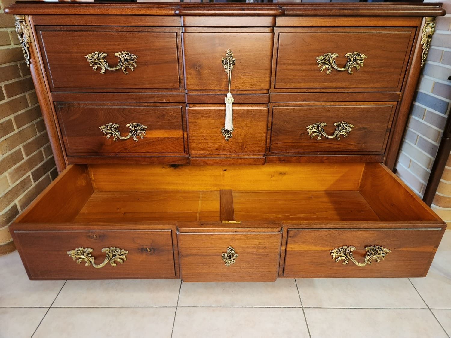 Cómoda de madera con varios cajones, algunos abiertos, herrajes de latón.