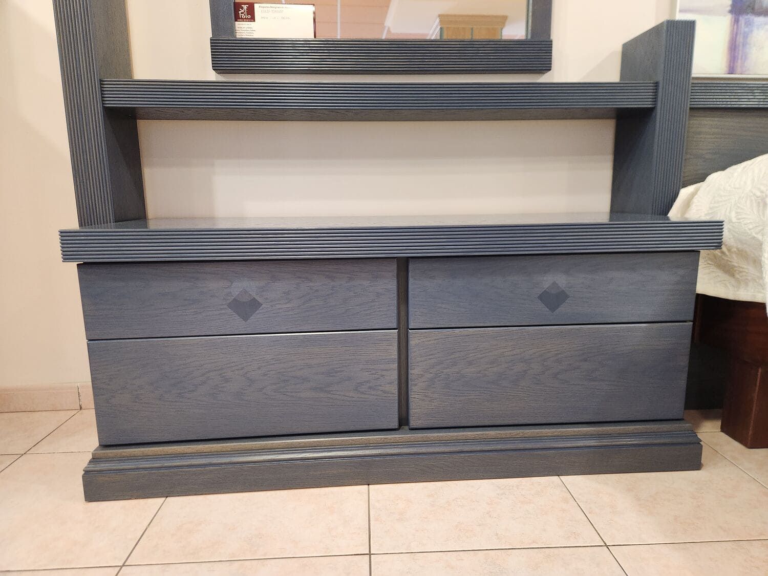 Cómoda de madera de color azul oscuro con dos cajones y un espejo encima.