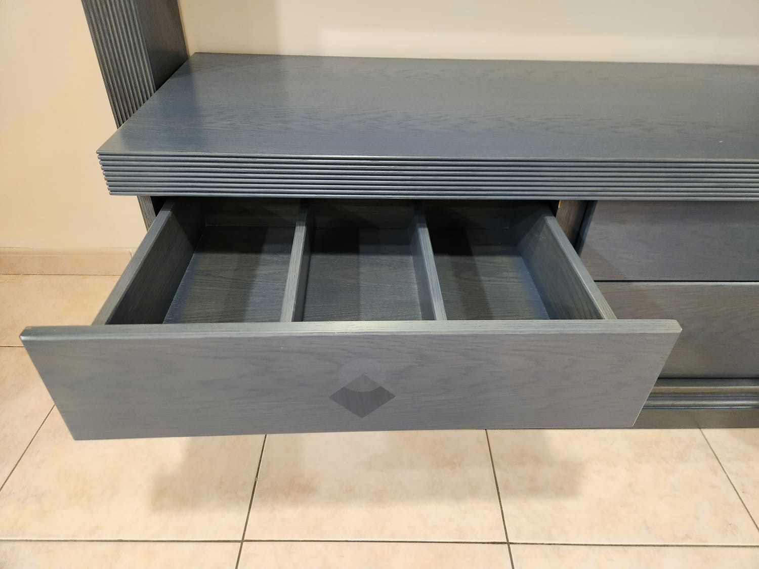 Cómoda azul con tres separadores, abierta. Diseño de rombos en el frente.