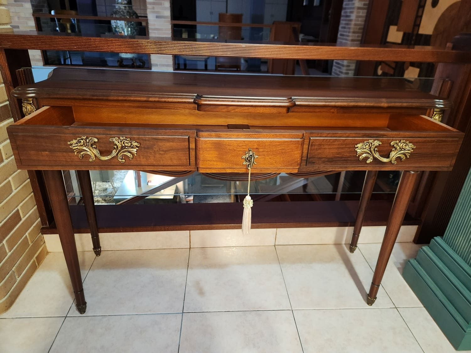 Escritorio antiguo de madera con cajones, herrajes de latón ornamentados y patas delgadas.