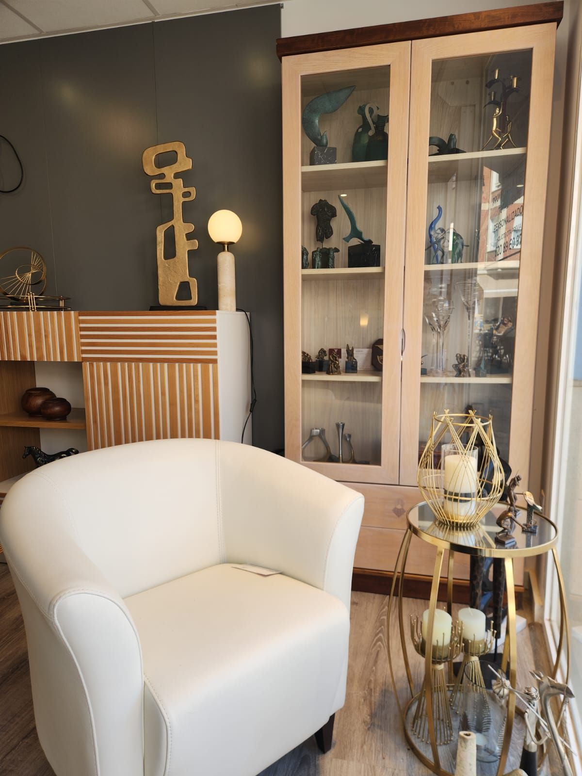 Una sala de estar con una silla blanca y una vitrina.