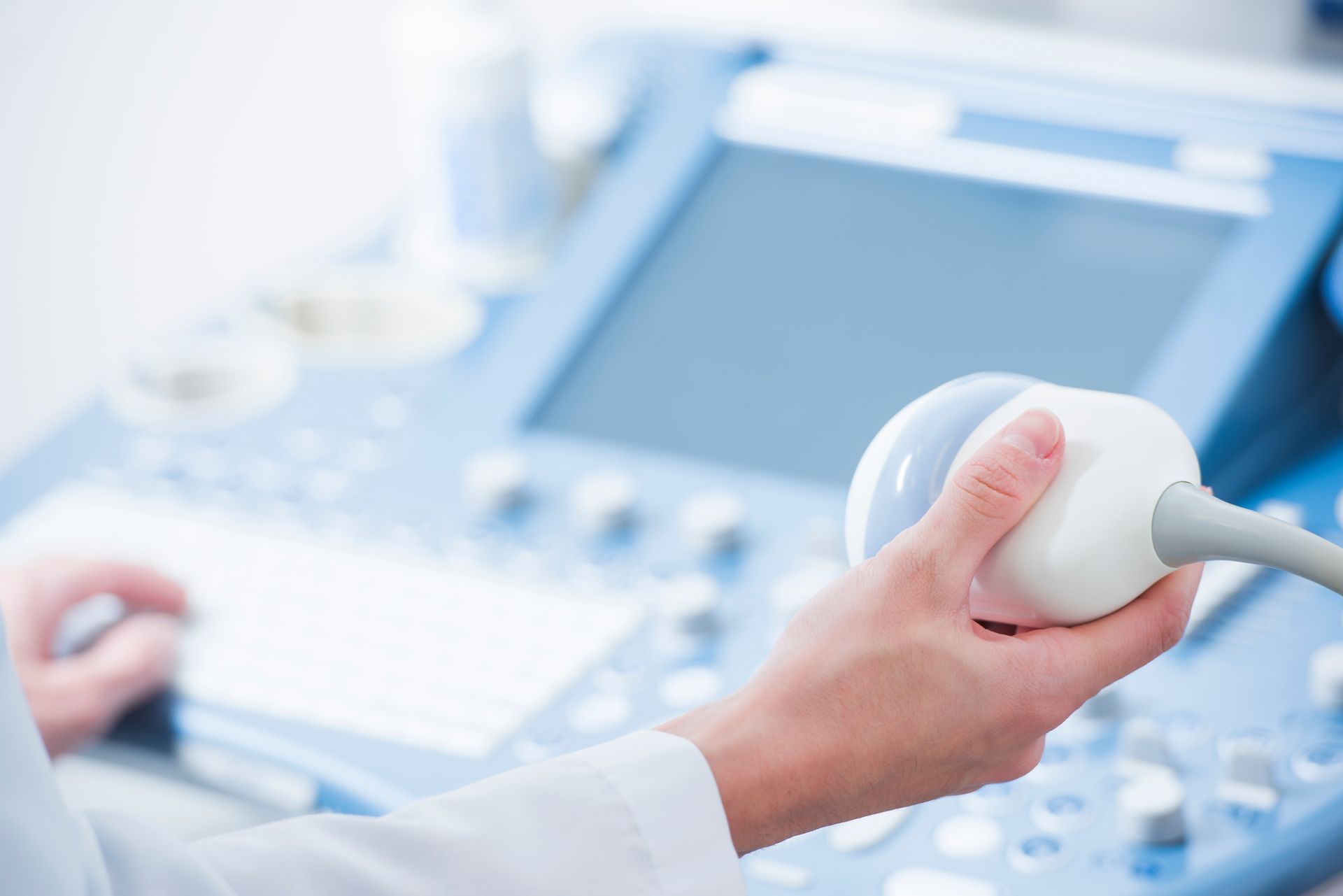 Gros plan sur les mains d'un médecin tenant une sonde pour échographie