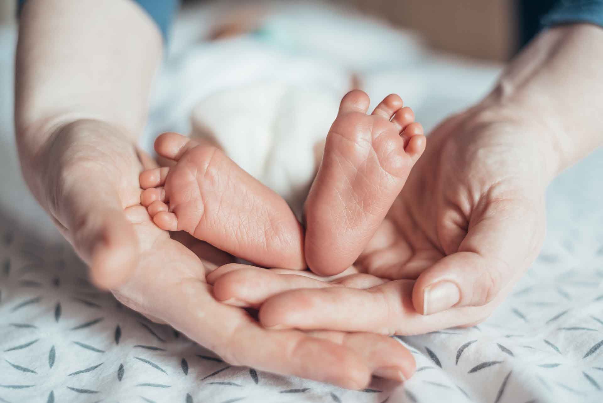 Soignante périnatale qui tient les pieds d'un nouveau né