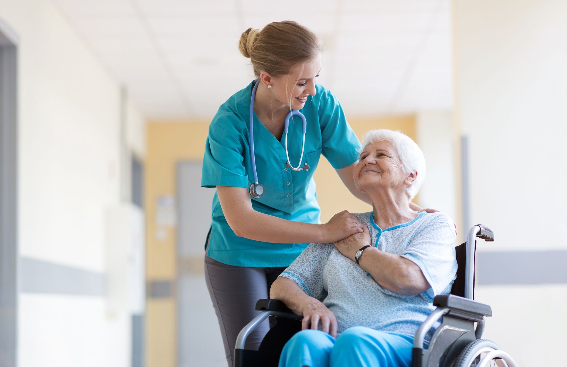 Une infirmière pose sa main sur l'épaule d'une dame âgée en fauteuil