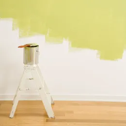 Escalera blanca pintando una pared de color amarillo pálido en una habitación con piso de madera.